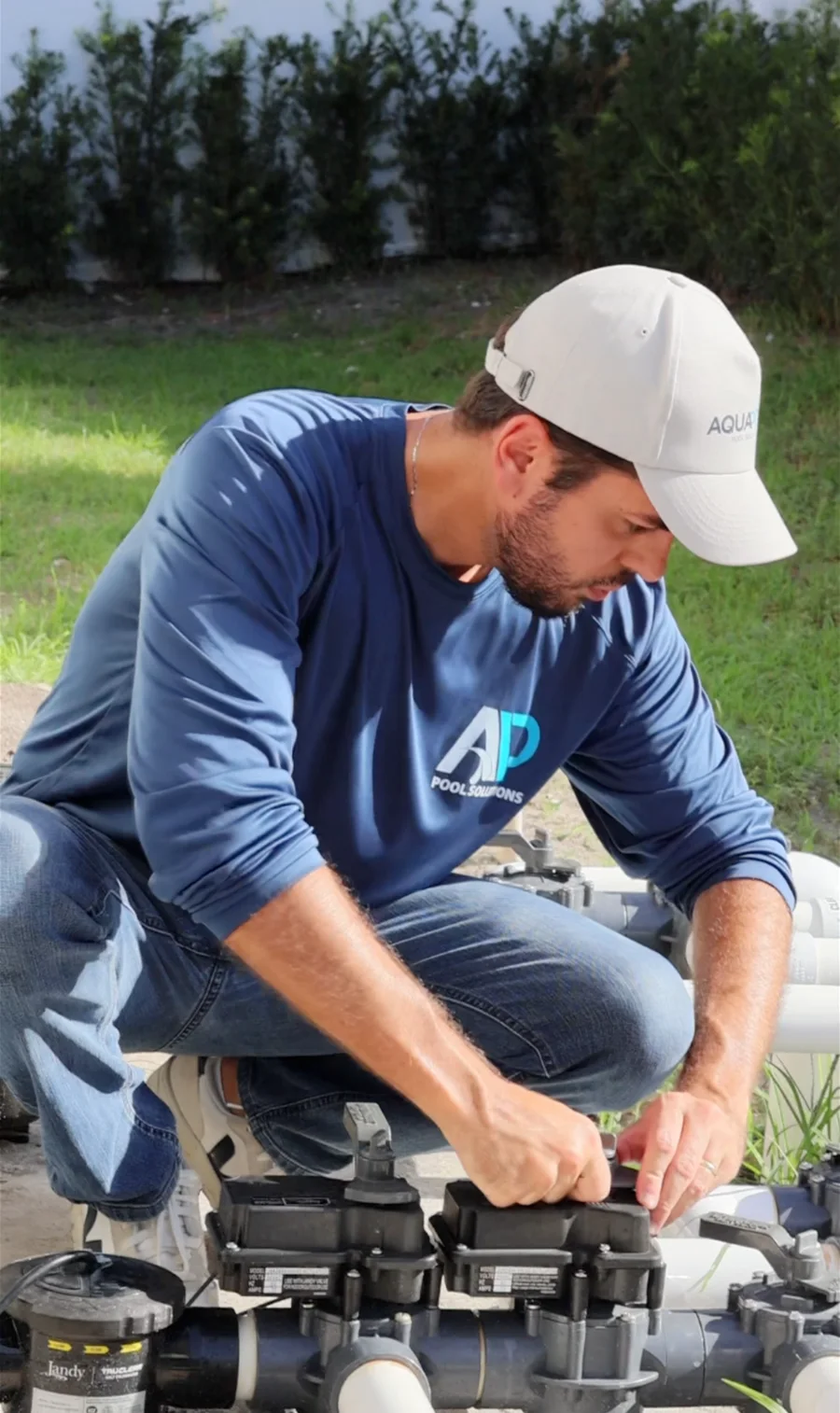 AquaPrime technician servicing pool equipment outdoors